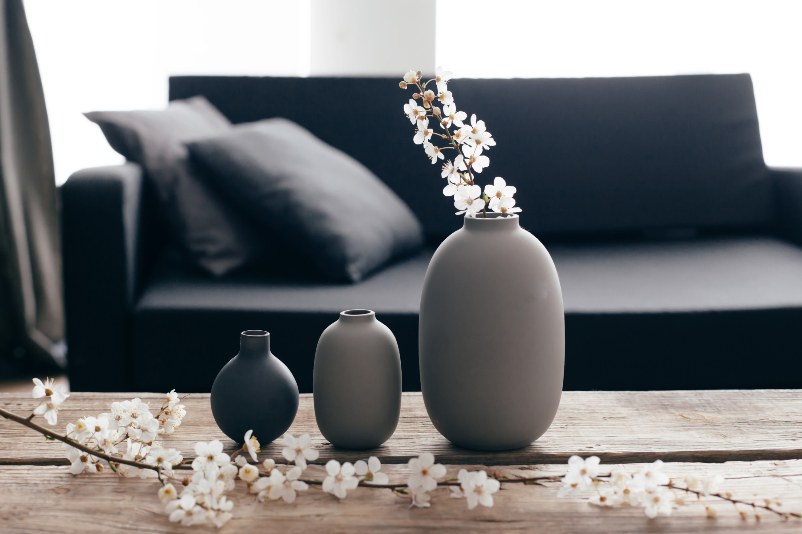 Three gray vases with cherry blossom branches sitting on a table