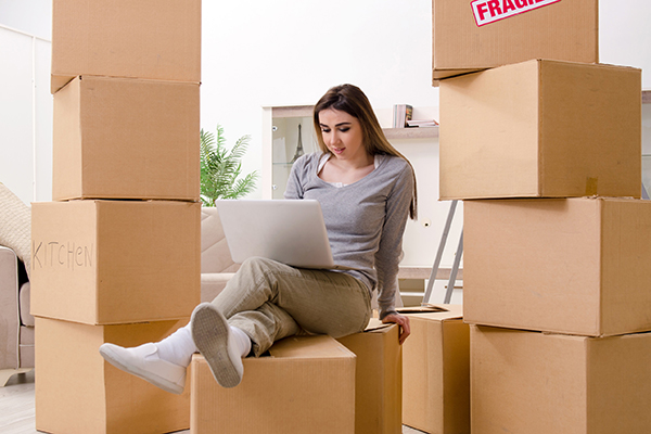 Woman sitting on boxes with laptop in her lap