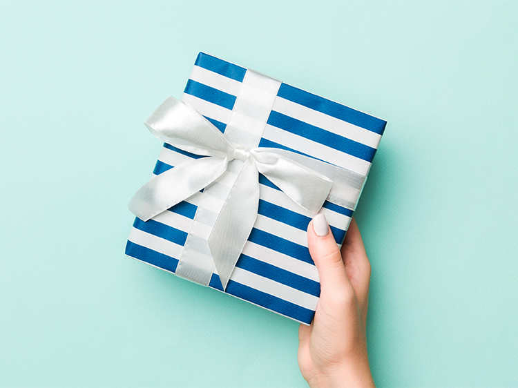 Hand holding out a blue striped present with a white bow