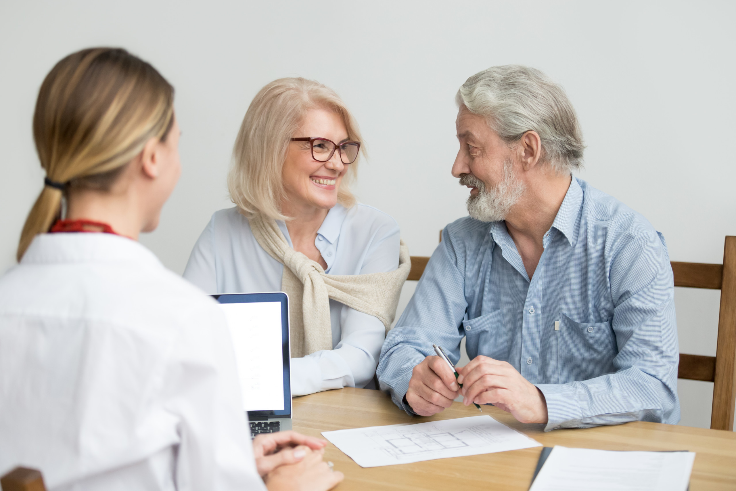 Happy senior couple deciding discussing new house purchase at meeting with agent, smiling older aged family consulting about buying home, taking mortgage loan, making investment or real estate deal